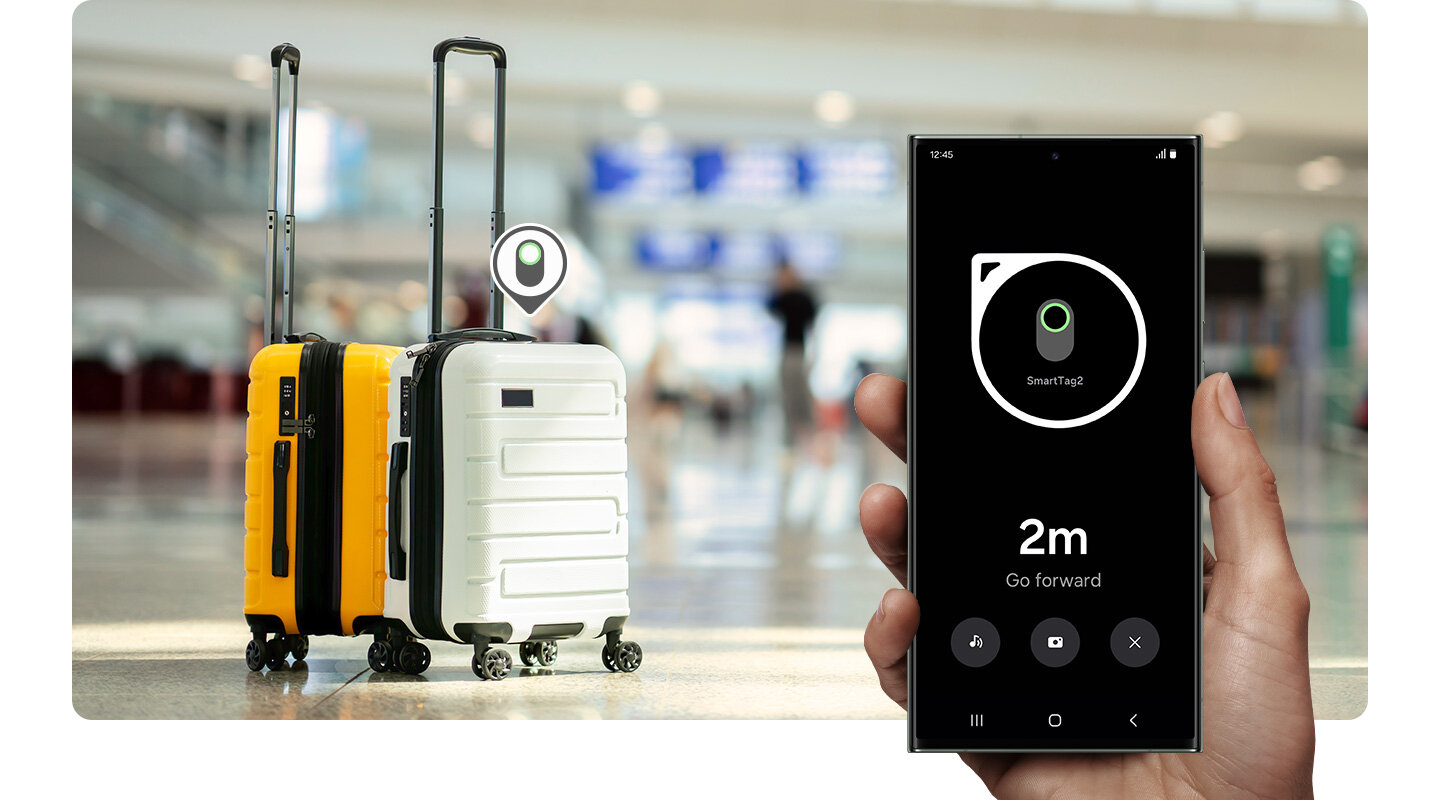 Alt-text: Smartfon Samsung Galaxy S23 Ultra trzymany w dłoni. Na ekranie wyświetlony Widok kompasu w ramach funkcji Szukaj w Pobliżu. W tle dwie walizki turystyczne w kolorach żółtym i białym stojące w hali lotniska. Nad walizkami widoczna ikonka lokalizowania urządzenia Samsung Galaxy SmartTag2.