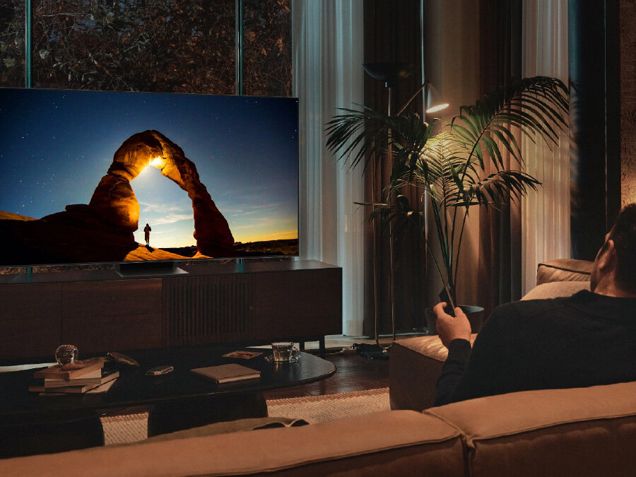Mężczyzna przed telewizorem QLED w nocy. Ekran wyświetla obraz zoptymalizowany w Trybie Komfortu dla Oczu. Q77BATXXH